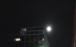 Last Cold moon iof the decade in the night sky above a tall building 