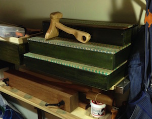 Finished tool boxes stack on shelf with veneer hammer.