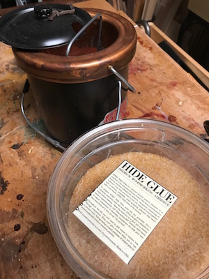 Copper hide glue pot and hide glue crystals on the woodbench.