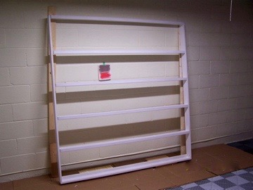 Primed album rack leaning on workspace wall with color paint samples.