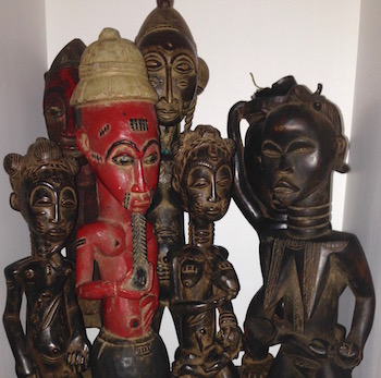 kwanzaa related arts from Africa with traditional dark statues and a red colored colonial statue