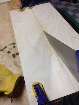 Sawing on the line on a panel of pine wood