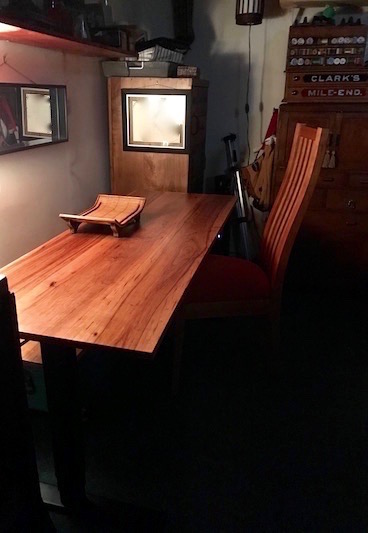 Self -care in the wood shop. Desk made from pecan wood with small tray on desk top. Slat back desk chair.