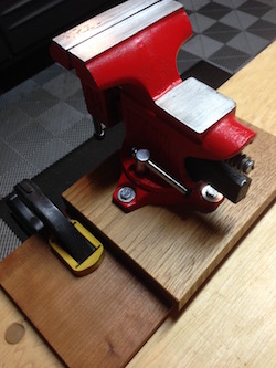 machinist's vise temporarily affixed to the wood bench with a clamp
