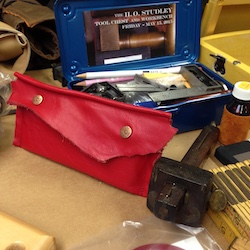 Orange leather plane blade pouch fastened up and ready to go to class.