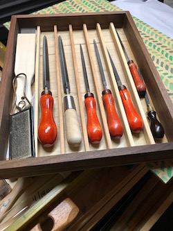 My saw file box filled with triangular saw files fitted with vintage wood handles, alongside a metal file for cleaning file teeth.