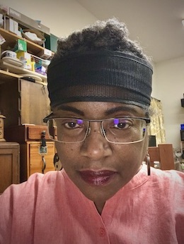 Shirley J in salmon color shirt and glasses in woodshop