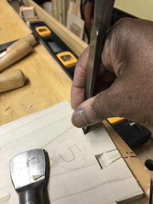 Chopping out dovetails with a chisel.