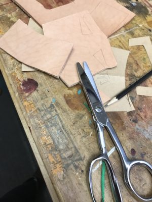 Leather and scissors used for making the cover or sheath pattern.