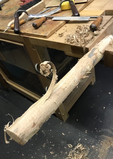 Shaped elm wood blank in bench vise. Drawknives in background.