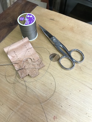 Hand-sewing the leather for the hook knife sheath.