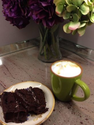 Digestif cup of coffee with foamed milk and slice of chocolate cake.