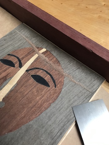 Veneers being leveled with a wood scraper.