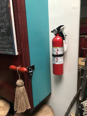 Fire extinguisher hanging on the wall next to a tool cabinet.