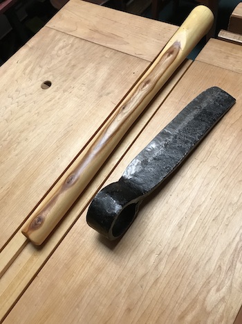 The elm handle beside the old forged froe blade on the wood bench.