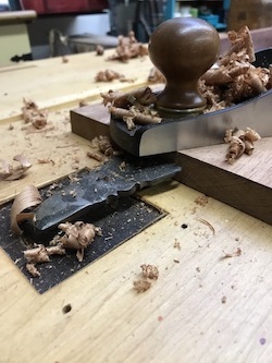 Bench stop in action with bench plane atop mahogany board for shop altar project.