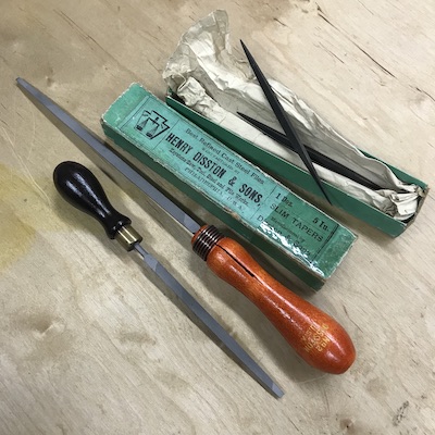 Saw files used for sharpening the teeth; vintage Disston saw file with original green box, other saw files with old wood file handles.