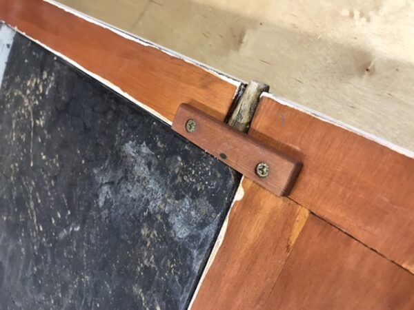 The longer upper door hinge.