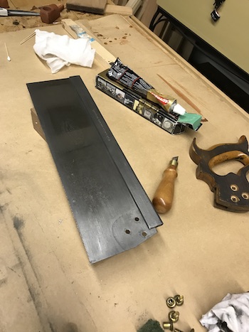 Saw blade after polishing alongside metal polish, saw screwdriver, and saw handle.