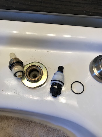 Old and new faucet cartridges around the metal washer.