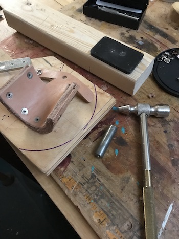 Rivets on underside of leather sheath shown with small hammer.