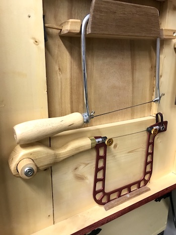 Fret saw and coping saw hanging in the saw cabinet.
