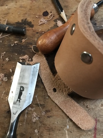 Leather sheath in process of being trimmed with chisel.