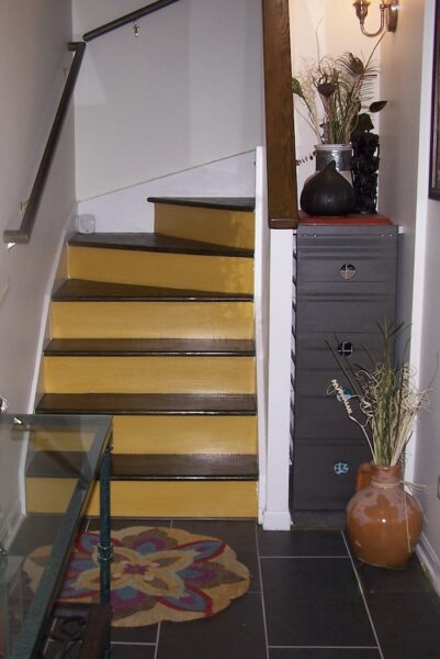 Entry view of newly renovated stairway with stained treads, painted risers and installed handrails.