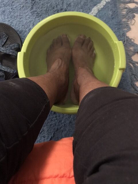 Soaking toes and feet in a green bucket.