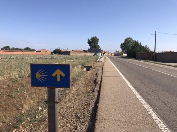 Camino road marker with yellow marker pointing the Way for a stranger on earth.