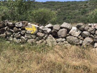 Stone wall marked with a yellow arrow.