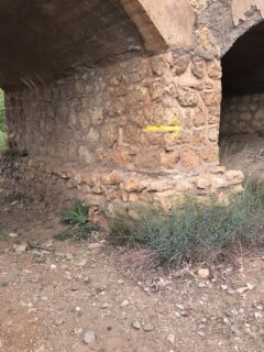 A yellow arrow on a stone bridge.