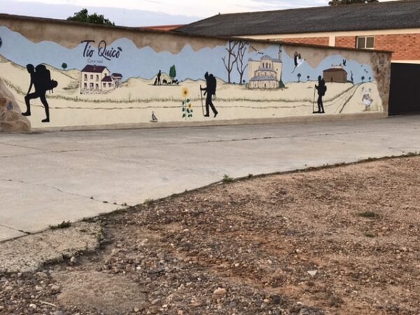 A mural depicting a camino family walking out of town.