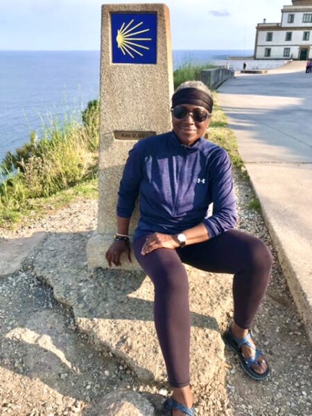 A peregrina sitting at the zero marker in Fisterra, Spain.