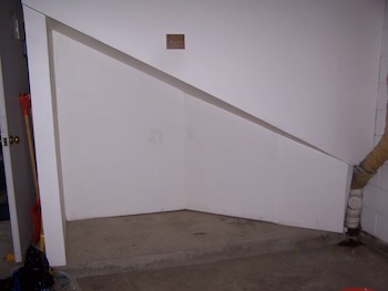 Empty garage storage space under the stairs.