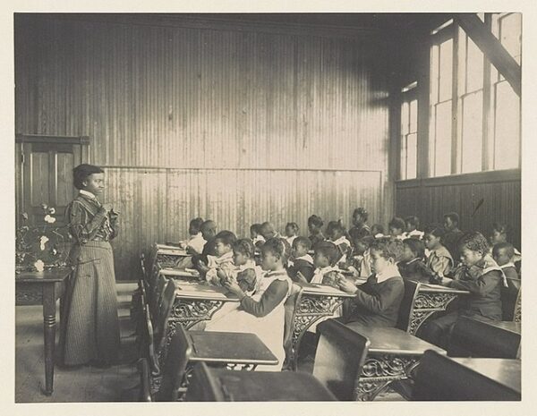 Black teacher and students learn in a classroom.