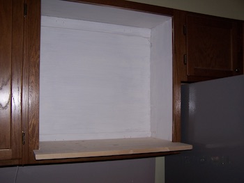 Sand and primed cabinet space for microwave space.