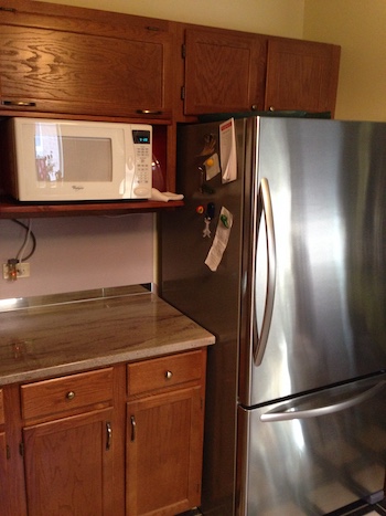 Microwave niche next to refrigerator in kitchen.