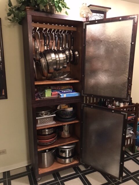 The pot rack and backers rack side by side in the kitchen - cabinet doors open.