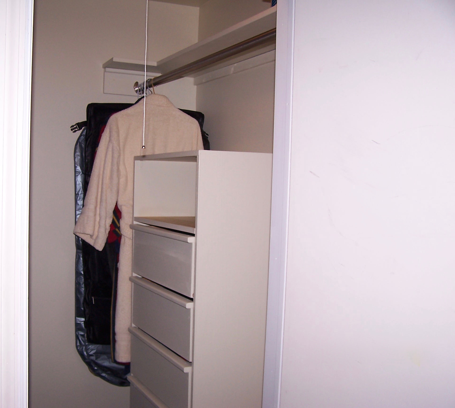 Clothes on the closet pole beside the hanging wall chest.